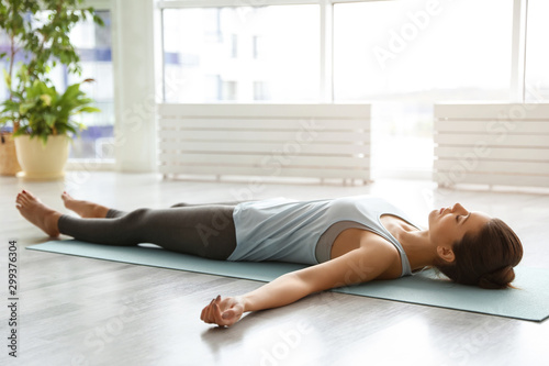 Young woman practicing corpse asana in yoga studio. Savasana pose photo