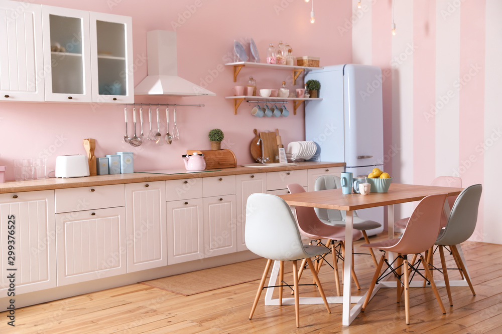 Stylish pink kitchen interior with dining table and chairs