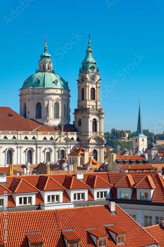 St. Nicolas church and and red roofs of Prague on a bright day with blue sky