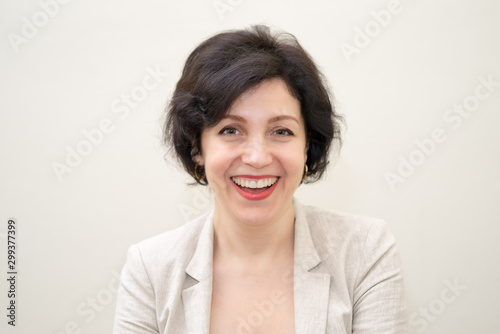 Pretty business woman, successful confidence hilarious laughing portrait with copy space. Attractive middle aged woman in business suit against concrete beige wall.