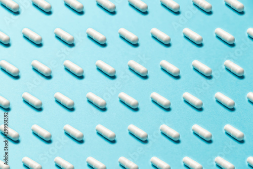 Trendy pattern made with Pharmaceutical medicine pills, tablets and capsules on bright light blue background. Medicine creative concepts. Minimal style with colorful paper backdrop. Trendy colors
