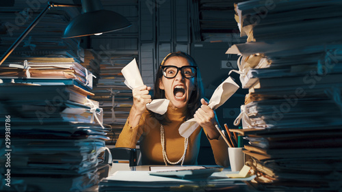Angry stressed office worker overloaded with paperwork photo