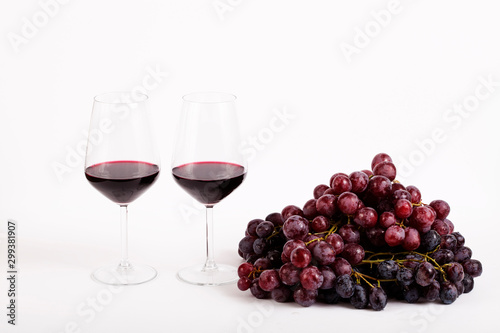 glass of red wine and grapes isolated on white background