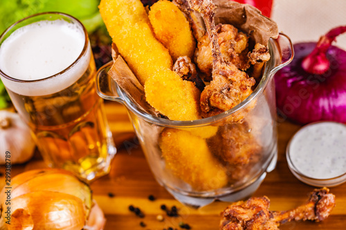 Fish fingers and fried chicken in glass bowl served with beer