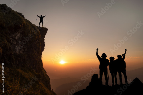 Group of friends having fun climbing on sunset and mountains backdrop, Young happy tourist on top of a mountain.
