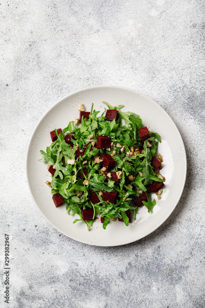 Fresh salad with arugula, feta cheese, walnut and beet on white plate. Beet salad Fresh salad with arugula, feta cheese, walnut and beet on white plate. Beet salad