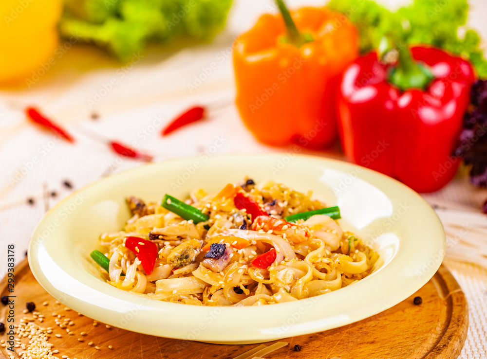 Pasta with seafood and vegetables in white plate on wooden cutting board Pasta with seafood and vegetables in white plate on wooden cutting board