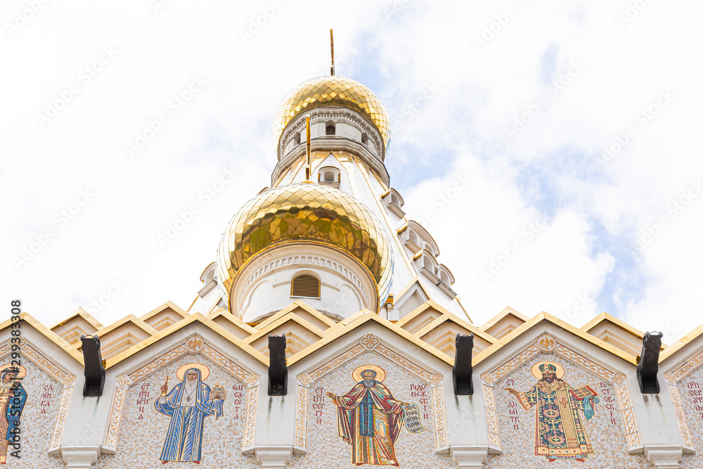 Bottom view of white church with gilt domes and images of saints