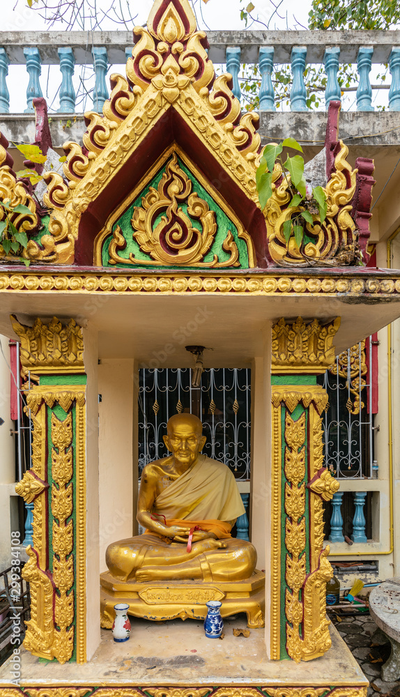Ko Samui Island, Thailand - March 18, 2019: Wat Laem Suwannaram Chinese Buddhist Temple. Golden statue of sitting old monk in gold-green baldachin niche. Two vases in front.