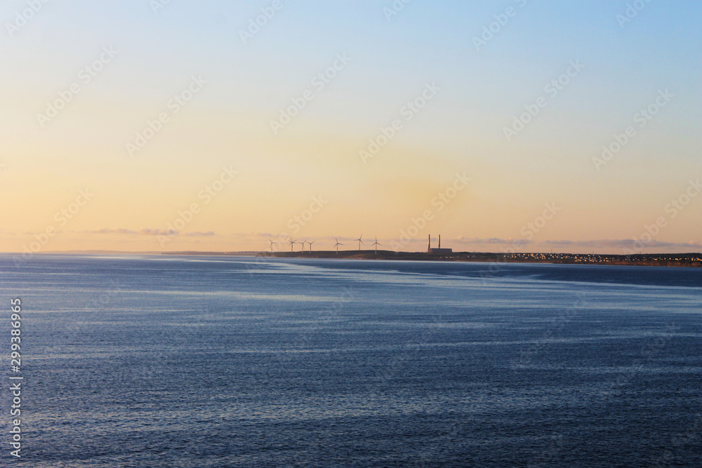 View of North Sidney, Nova Scotia, looking in from the sea. Land is on the horizon. Wind turbines visible on the point.
