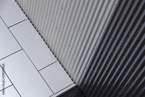 Close-up of corner of building - junction of white smooth tiled wall and metal corrugated black and white wall