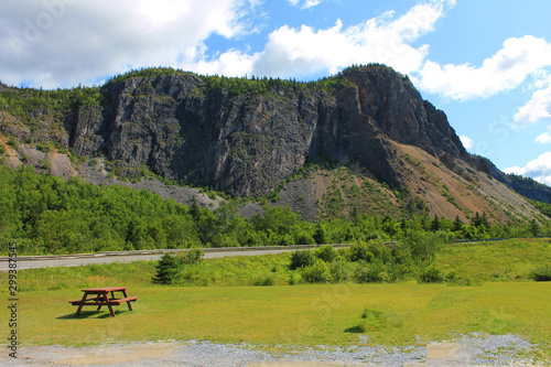 Looking from roadside rest area at Breakfast Mountain, where the man in the mountain natural rock formation can be found, Corner Brook, Newfoundland Labrador. Sunny summer day, blue sky with light clo