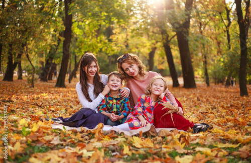 Portrait of happy family in forest park in autumn colorful landscape, motherhood and carefree childhood in nature outdoors © okostia