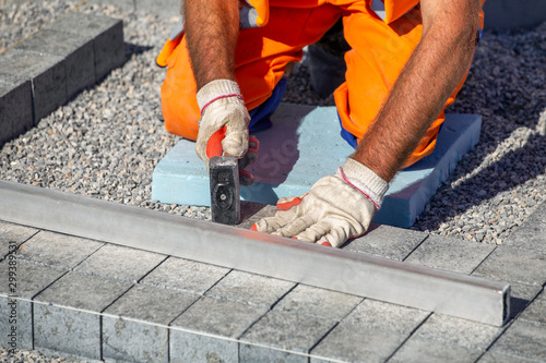 Builder gloved hands laying paving bricks