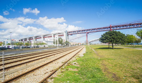 Railroad that crossing below the Ponte 25 de Abril bridge - Over 2km-long, this striking Golden Gate-style bridge links Lisbon with Almada in Portugal. captured at the promenade in Lisbon side. 
