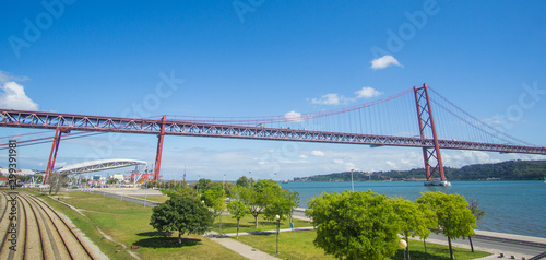 Railroad that crossing below the Ponte 25 de Abril bridge - Over 2km-long, this striking Golden Gate-style bridge links Lisbon with Almada in Portugal. captured at the promenade in Lisbon side. 