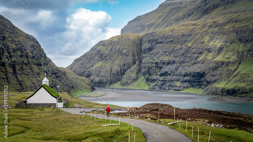 Unidentified man walking towards church from village of Saksun, Faroe Islands, Denmark photo