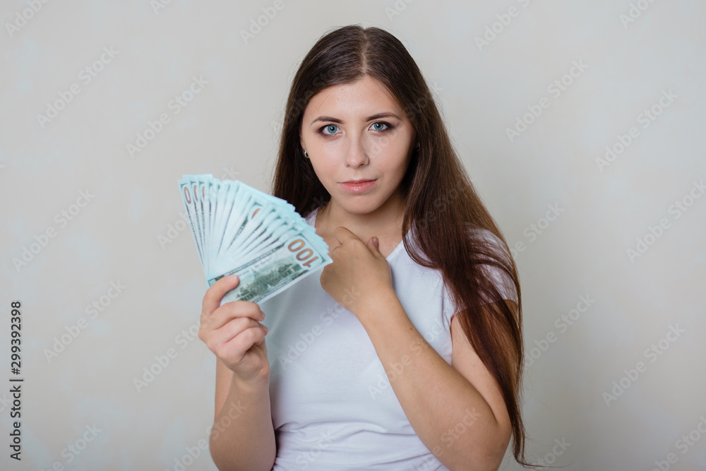young, beautiful girl in a white T-shirt with money in hands young, beautiful girl in a white T-shirt with money in hands