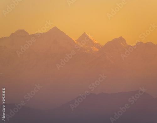 The yellow-orange morning light hits the scenic Himalayan peaks in the Indian town of Kausani in Kumaon in the state of Uttarakhand  India.