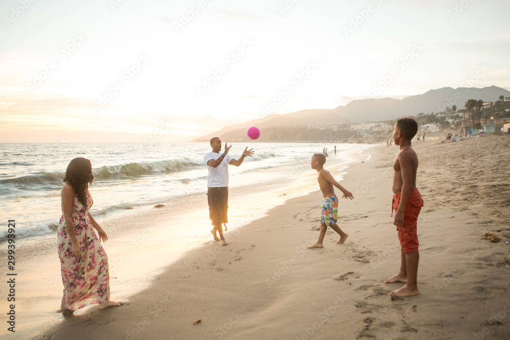 Family playing at the beach at sunset