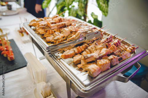 A lot of cooked fried roasted grilled meat or fish from a grill or oven lies on a metal tray. Photo for restaurant or stand-up meal or banquet. Delicious tasty food at the party. photo