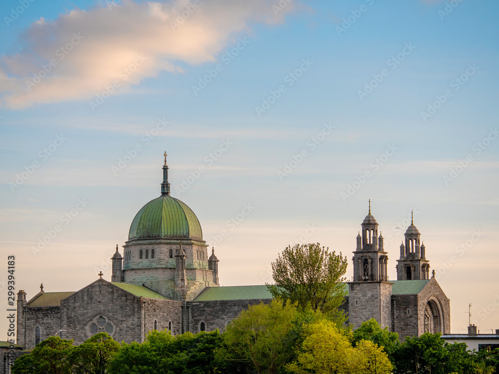 Galway Cathedral behind green trees, Beautiful blue cloudy sky, Ireland, Town's landmark building.