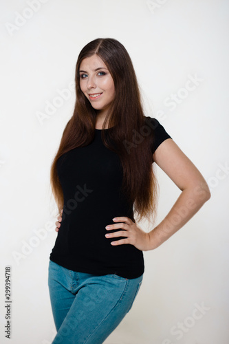 Young, beautiful girl in a black T-shirt and blue jeans. Studio photo on a white background. © Михаил Гута