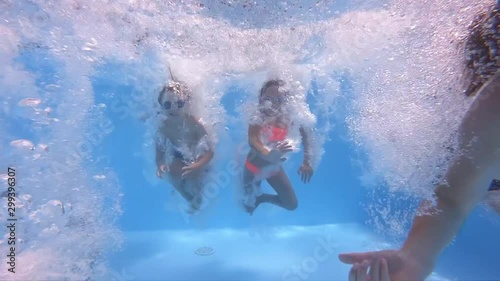 Underwater view of having fun group of children jumping and diving into swimming pool at pool party in summer sunny day. Happy children. Slow motion. Childhood, friendship, vacation concept