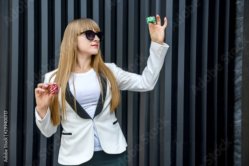 Stylish business woman with poker chip on grey background. Online casino concept photo