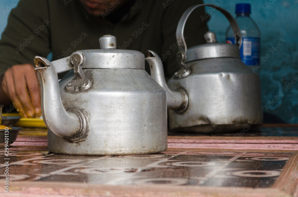 Two old aluminum kettles used to serve water in a rustic village restaurant Two old aluminum kettles used to serve water in a rustic village restaurant