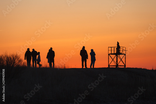 Silhouettes of people enjoying sunset on the coast of the sea