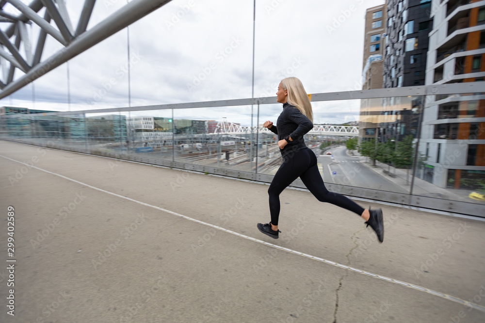 Female jogger in black workout outfit in modern city environment Female jogger in black workout outfit in modern city environment
