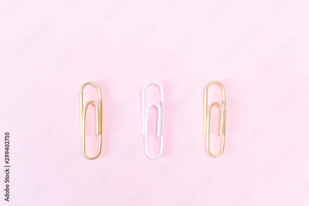 Pink and golden paper clips on a pastel pink background. The concept of stationery, study, office, business. Minimalism.