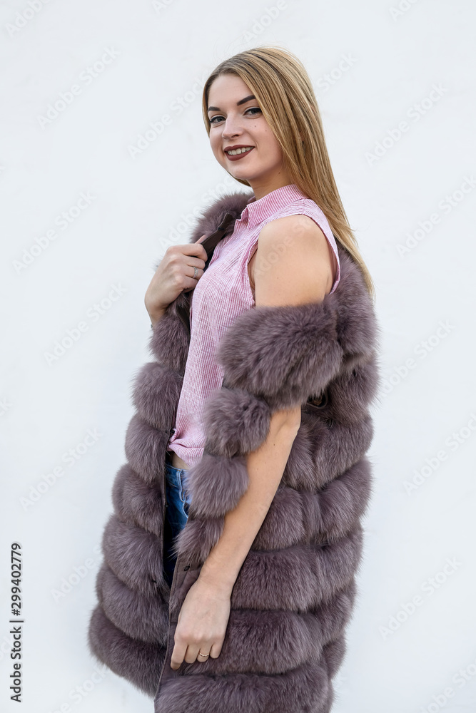 Beautiful young woman in fur coat on white wall. Beauty and fashion. Beautiful young woman in fur coat on white wall. Beauty and fashion.
