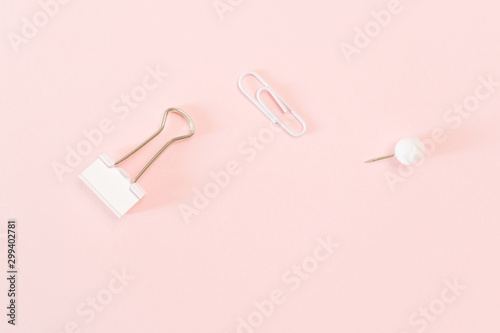 Pinkish paper clips and thumbtack on a pastel pink background. The concept of stationery, study, office, business. Minimalism.