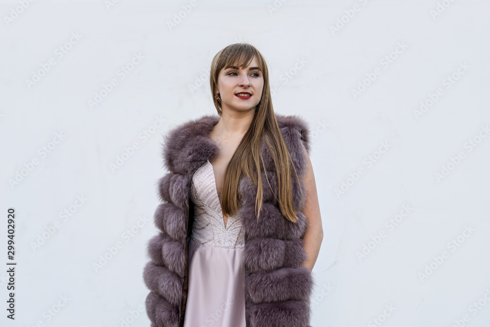 Beautiful young woman in fur coat on white wall. Beauty and fashion. Beautiful young woman in fur coat on white wall. Beauty and fashion.