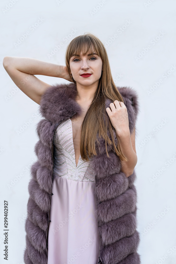 Beautiful young woman in fur coat on white wall. Beauty and fashion. Beautiful young woman in fur coat on white wall. Beauty and fashion.