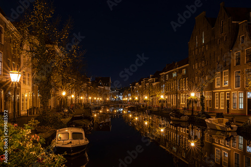 A night shot from the old bridge (The Kerkbrug) on the Oude Rijn with numerous boats and illuminated old canal-side houses, Leiden, the Netherlands