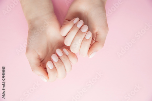 Beautiful female hands with gel polish manicure on pink background, top view