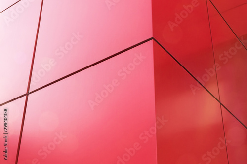 Geometric color elements of the building's facade with planes, lines, corners with highlights and reflections for an abstract background and texture of red, orange colors. Place for text