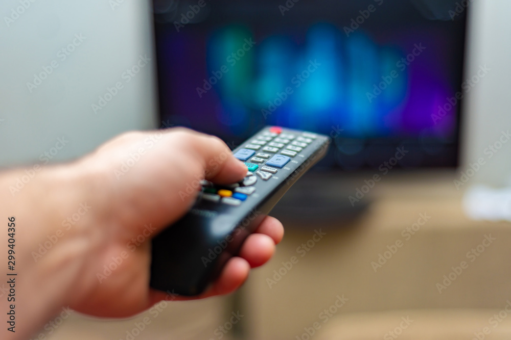 A man watches tv and holds the shift control with his left hand. A man watches tv and holds the shift control with his left hand.