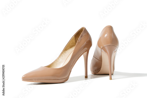 Close up shoe women. Beige patent female leather shoes isolated on white background. Woman high heels footwear on floor. Fashion and shopping concept. Top view. Copy space. Selective focus.