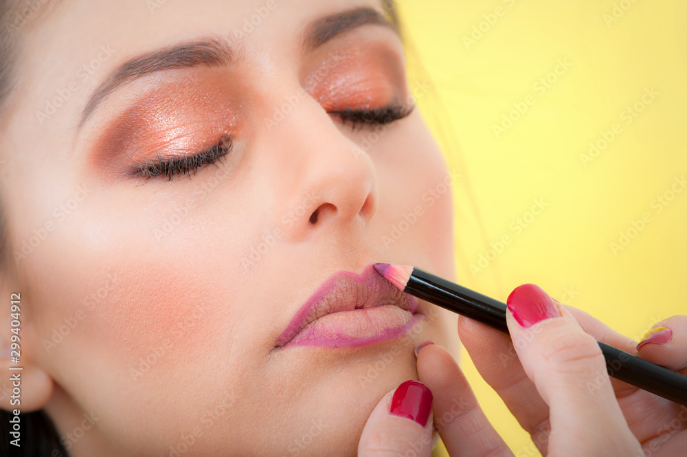 Makeup professional artist applying lipstick on lips with pencil