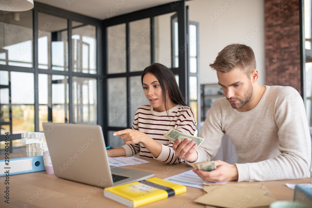 Husband counting money while filling tax declaration Husband counting money while filling tax declaration