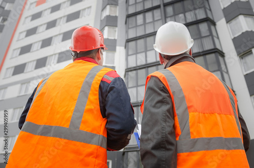 An engineer with a hard hat and helmet discussing a project at a construction site with a team leader in autumn or winter. architecture construction concept. Industrial safety