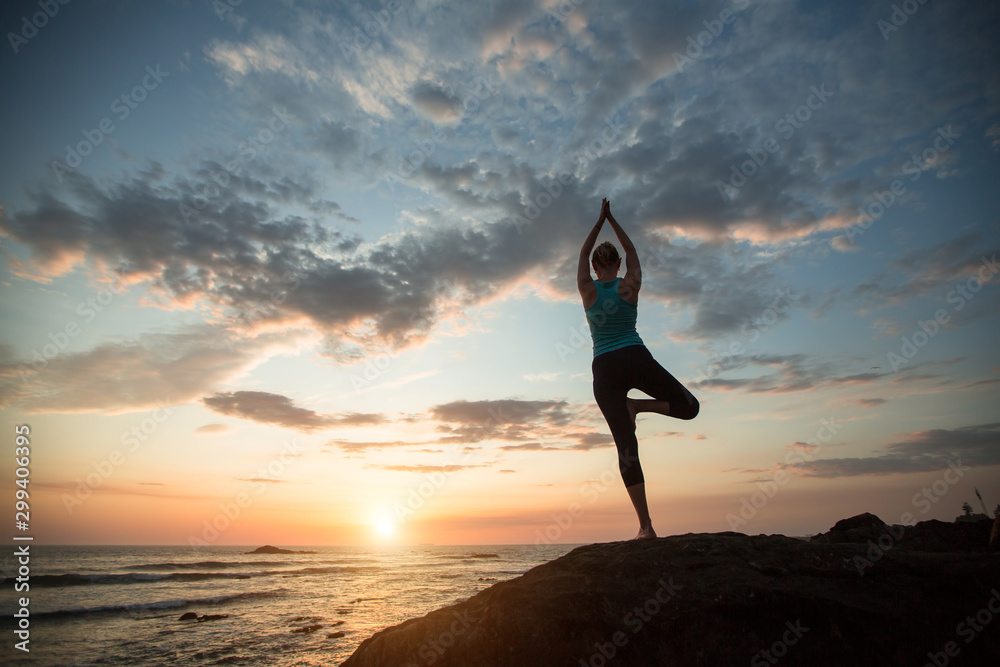 Yoga woman sees off the sun on the ocean coast. Exercises.