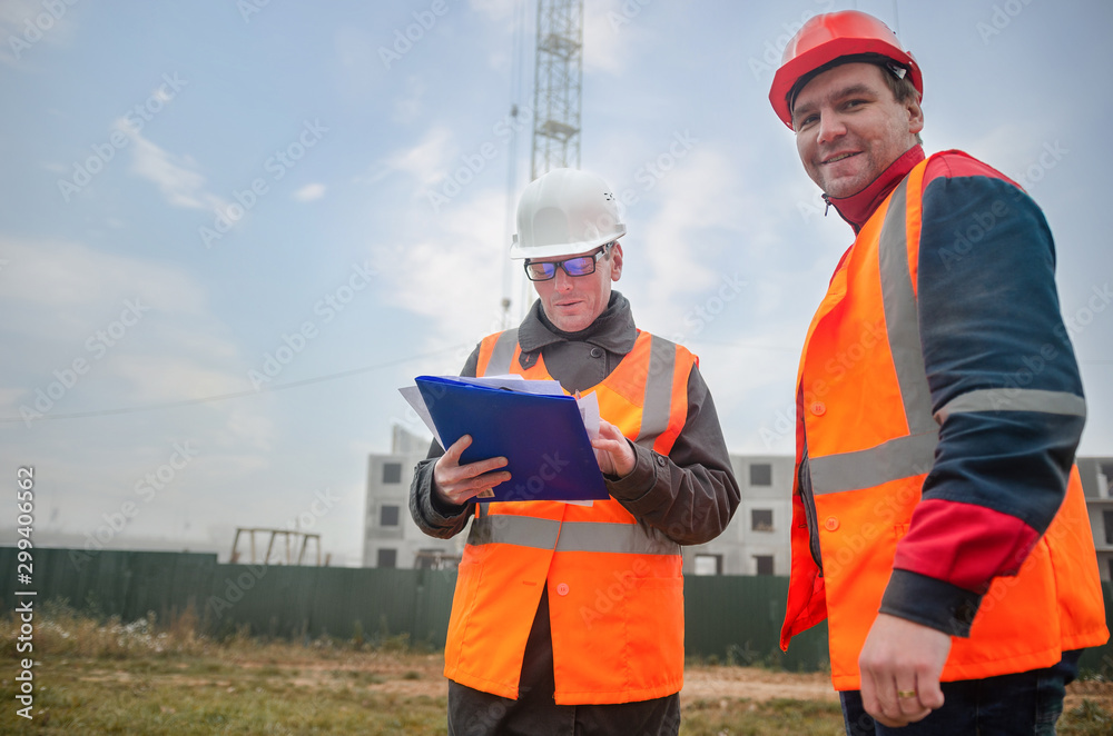 An engineer with a hard hat and helmet discussing a project at a construction site with a team leader in autumn or winter. architecture construction concept. Industrial safety