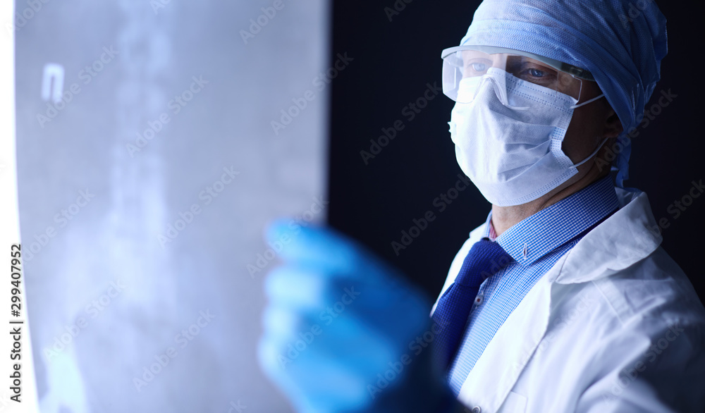 Fototapeta premium Young doctor looking X-Ray image on isolated white background