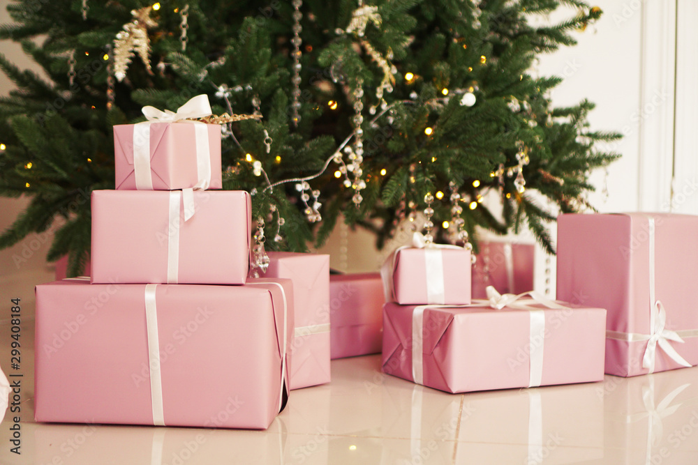 Pink present boxes with ribbons under the Christmas tree in Classic apartments with white interior