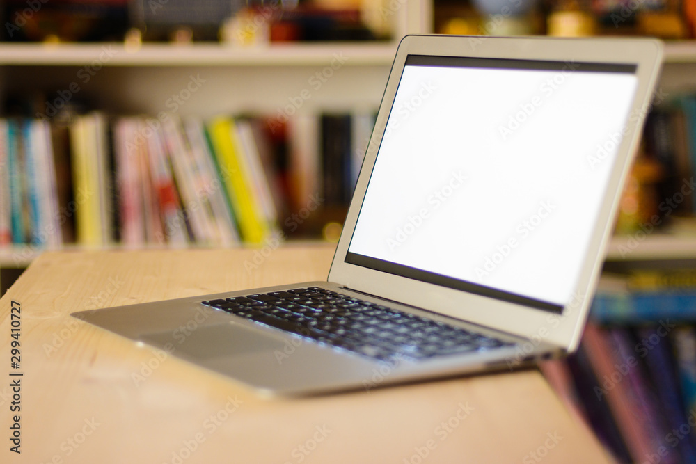 Notebook computer in library, room full of books